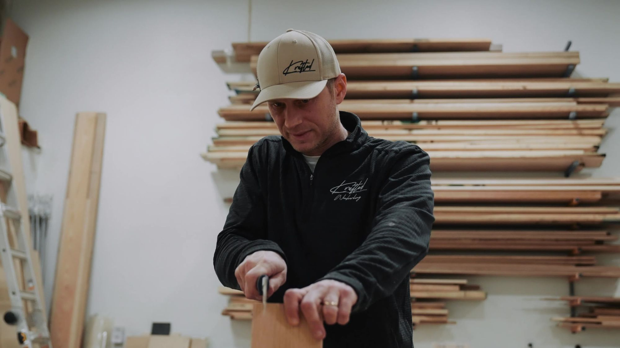 Working the end of a board by hand, lumber racks behind